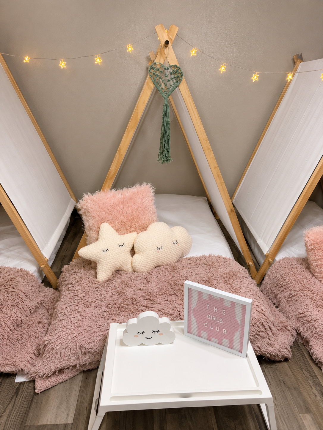 Pink-themed sleepover with fluffy blankets, star and cloud pillows, and Girls Club sign